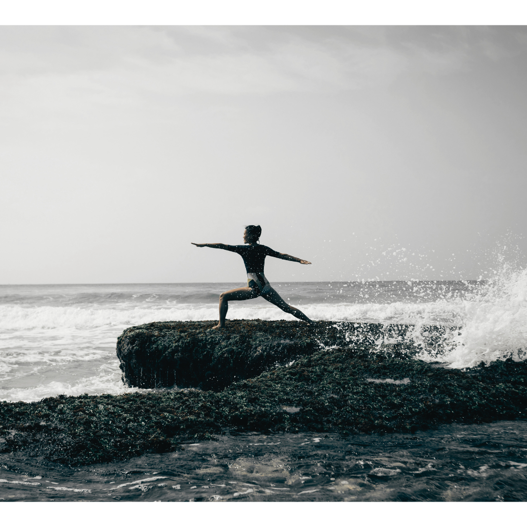 Yoga Frau_Krieger_Position_Meer_Wellen sprizen gegen Felsen